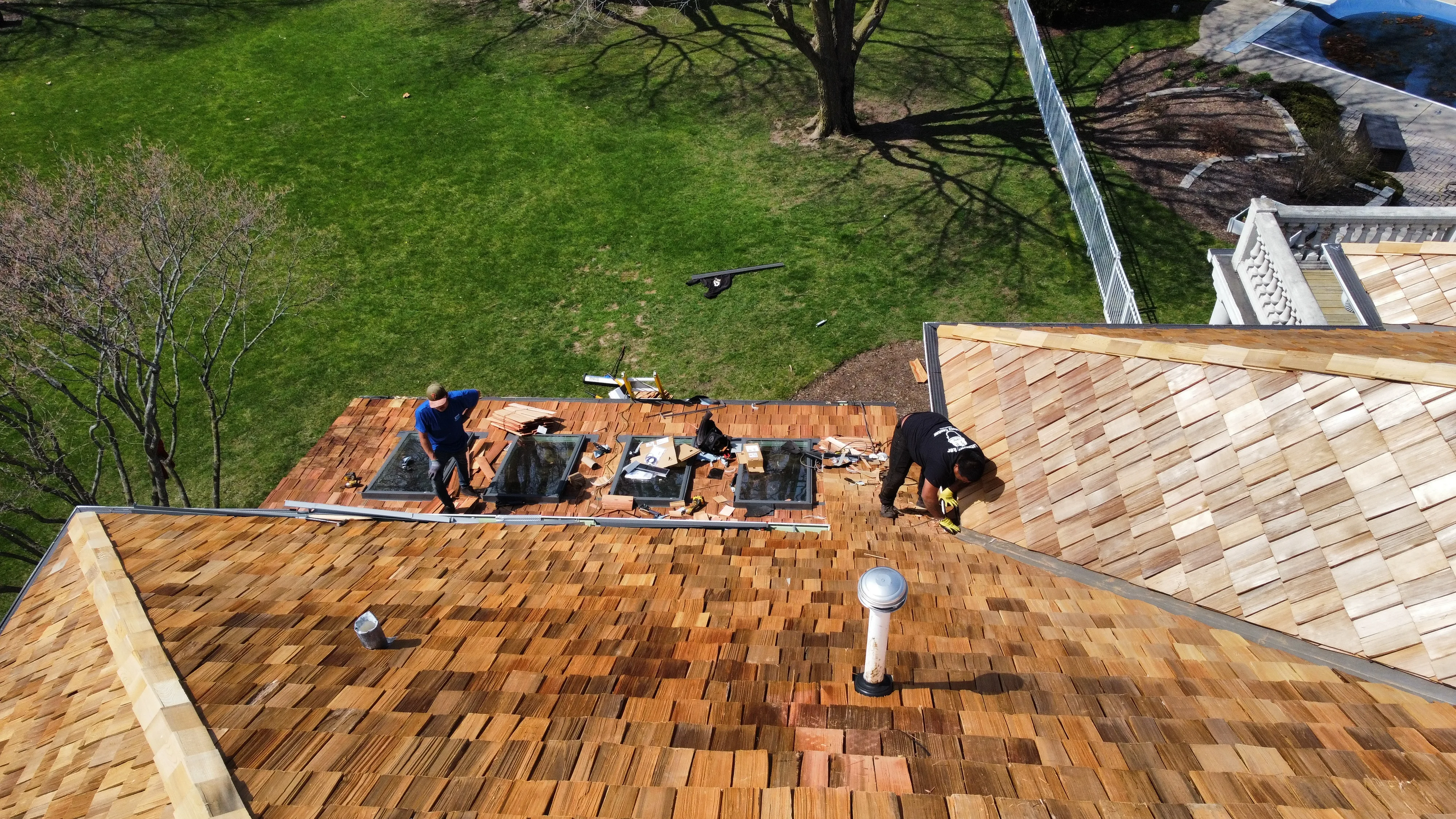 Crew working on roof replacement with materials staged