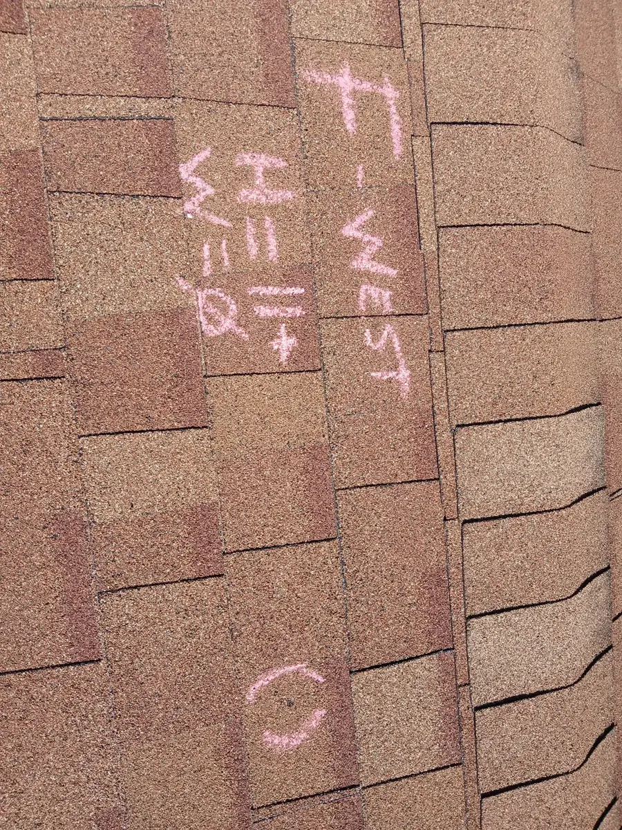 Chalk on a shingle roof reading F-WEST, H=11, W=0, with a circled hail hit below it