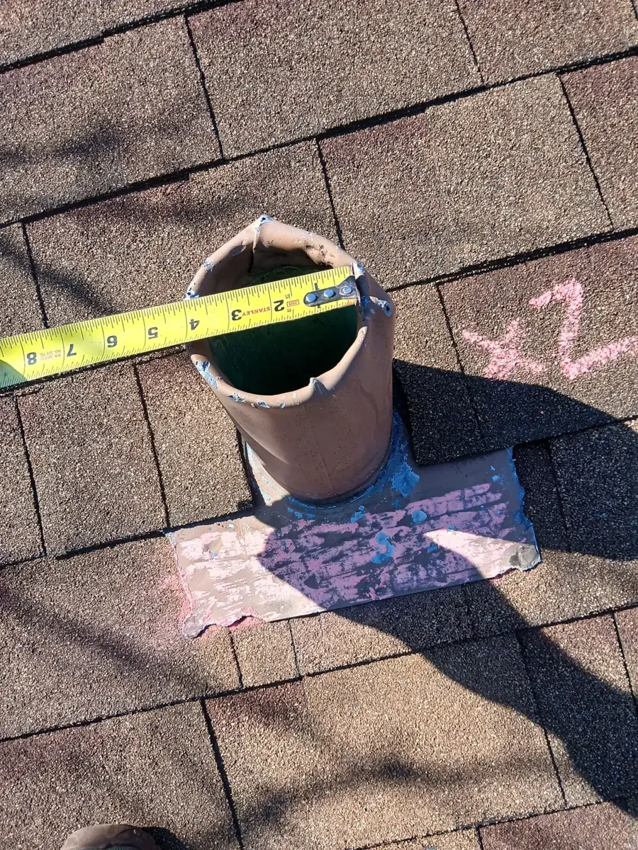 A tape measure across a roof pipe with x2 chalked beside it