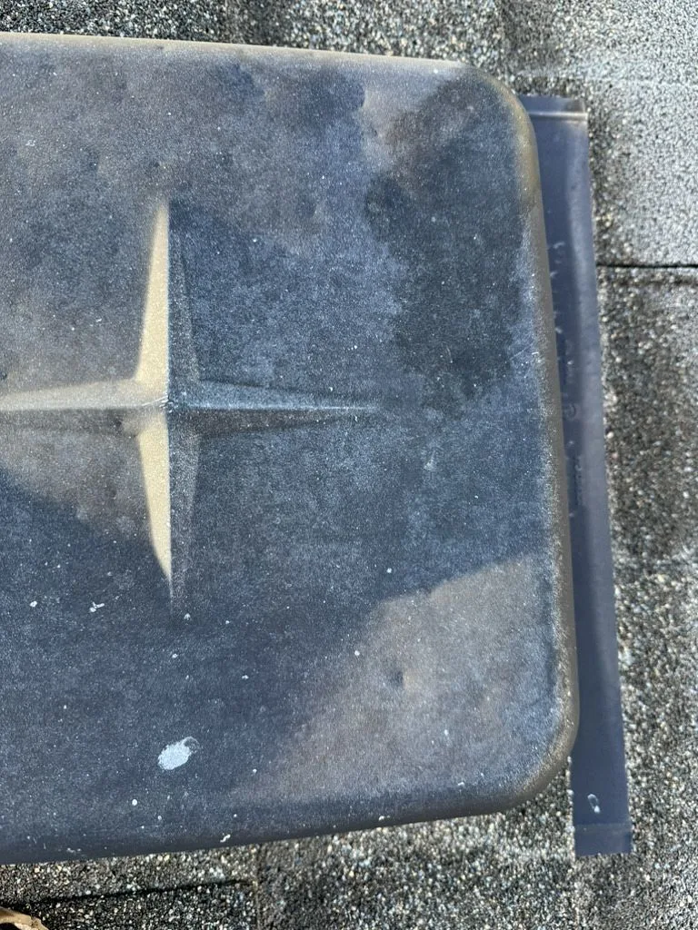 Roof vent showing weathering and damage on shingle surface