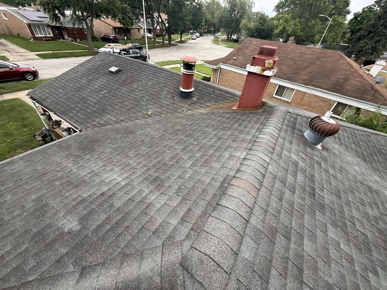 A gray asphalt architectural shingle roof with multiple chimneys and vents in Alsip, IL