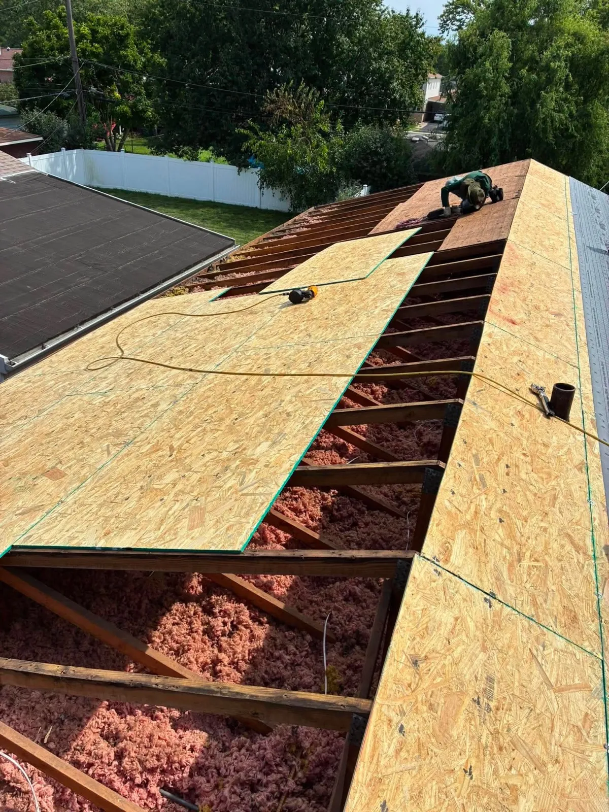 A roofing crew installs oriented strand board (OSB) sheathing over a roof deck in Alsip, IL