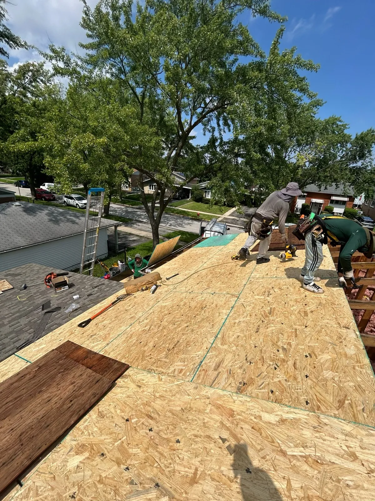 Workers installing oriented strand board (OSB) sheathing on a roof in Alsip, IL