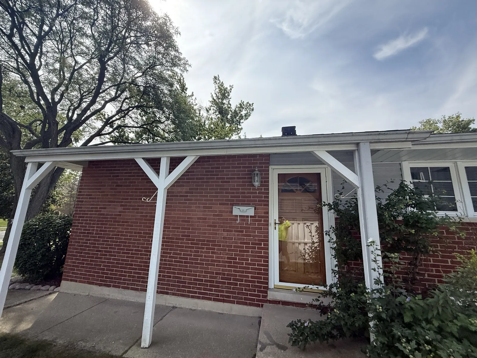 A view of a brick home with a white porch overhang and a shingled roof in Arlington Heights, IL