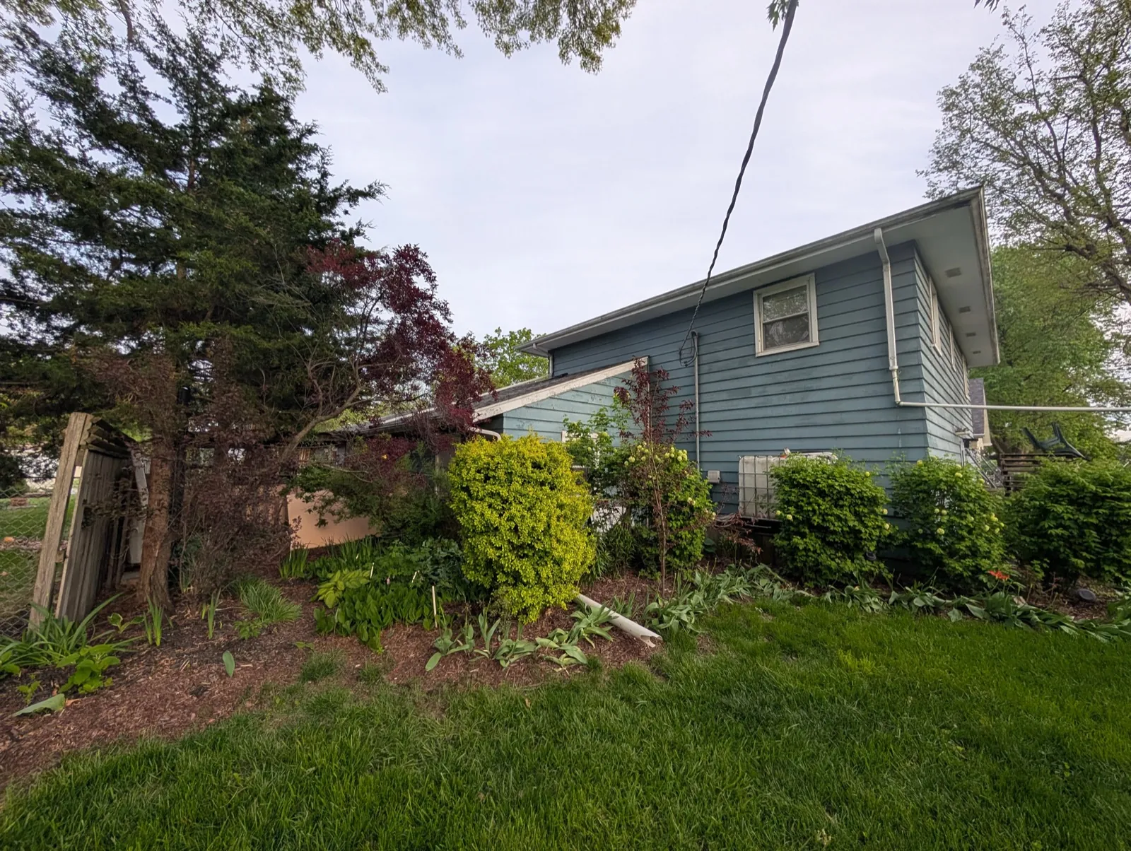 Blue vinyl siding on a residential home with a surrounding garden in Aurora, IL