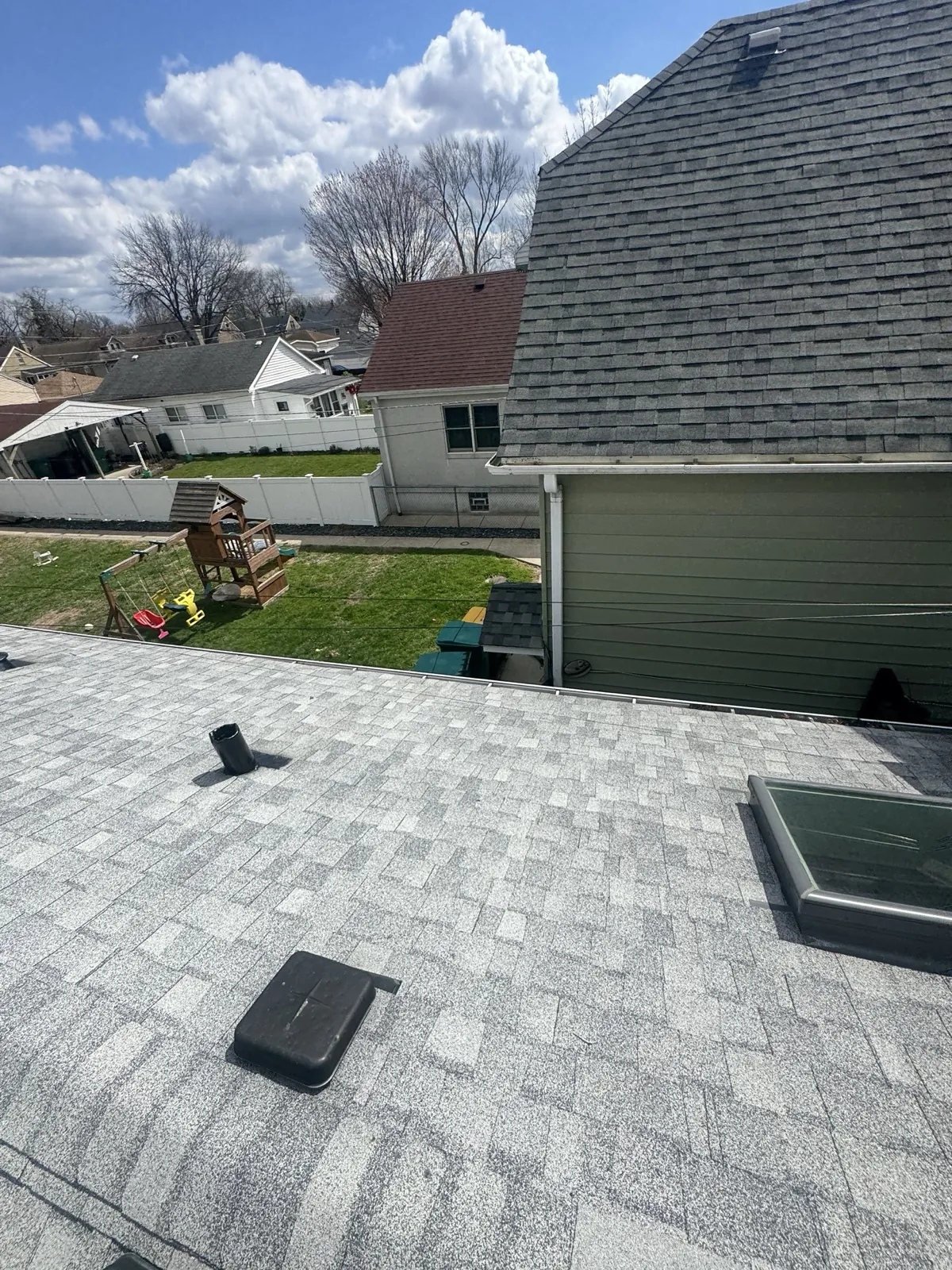 A gray asphalt architectural shingle roof featuring a skylight and ventilation pipes in Berwyn, IL
