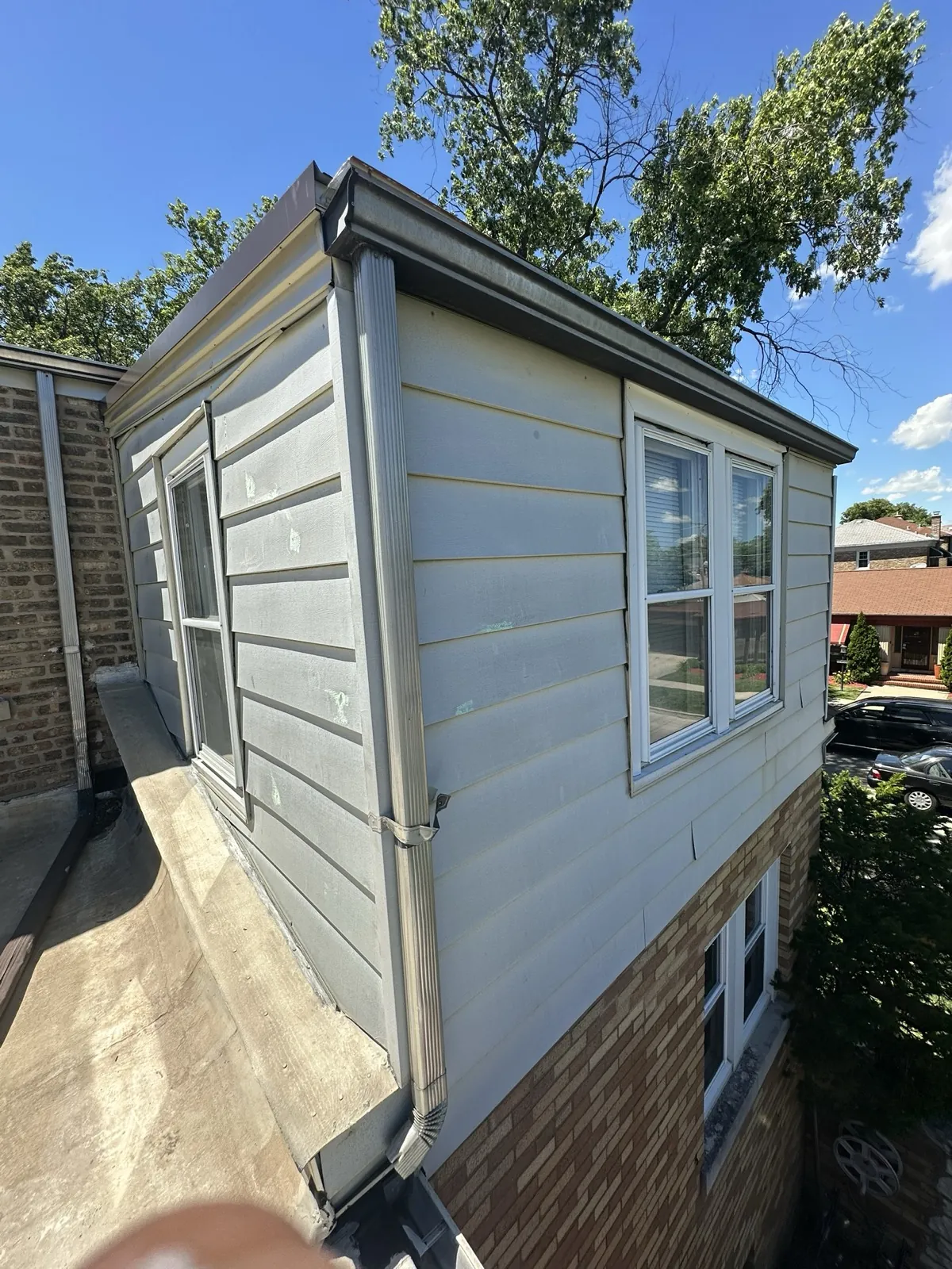 New aluminum gutters and downspouts installed on a house with white siding in Berwyn, IL