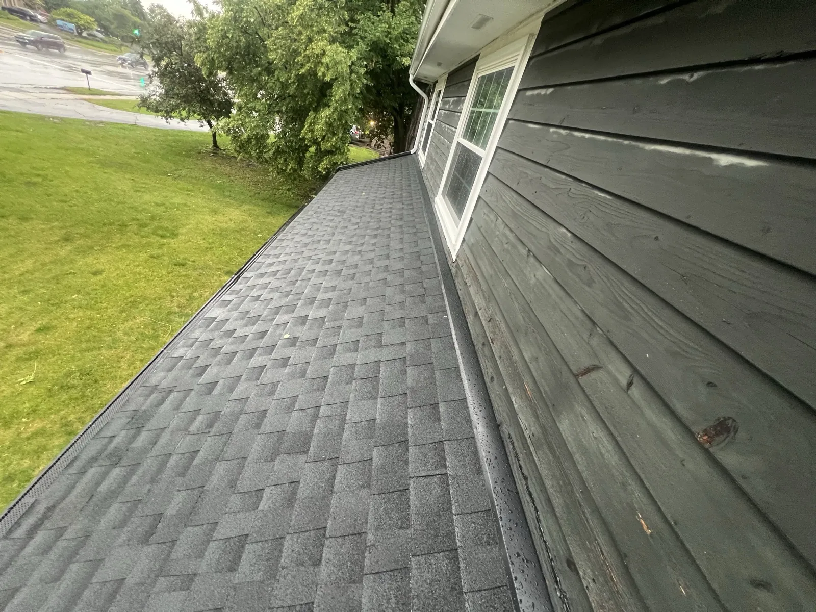 New charcoal gray architectural shingle roof on a home with dark wood siding in Bloomingdale, IL