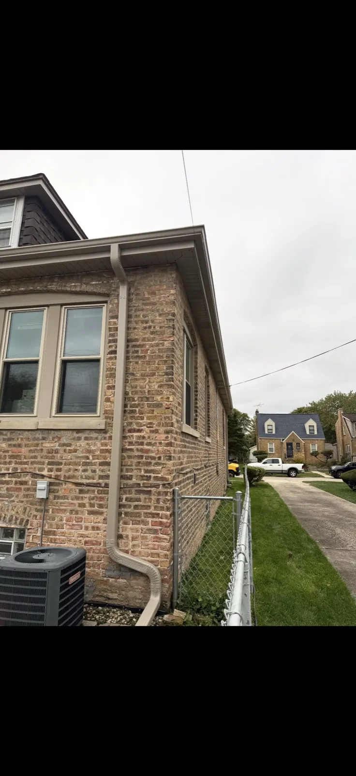 New tan gutters and downspouts installed on a brick home in Brookfield, IL