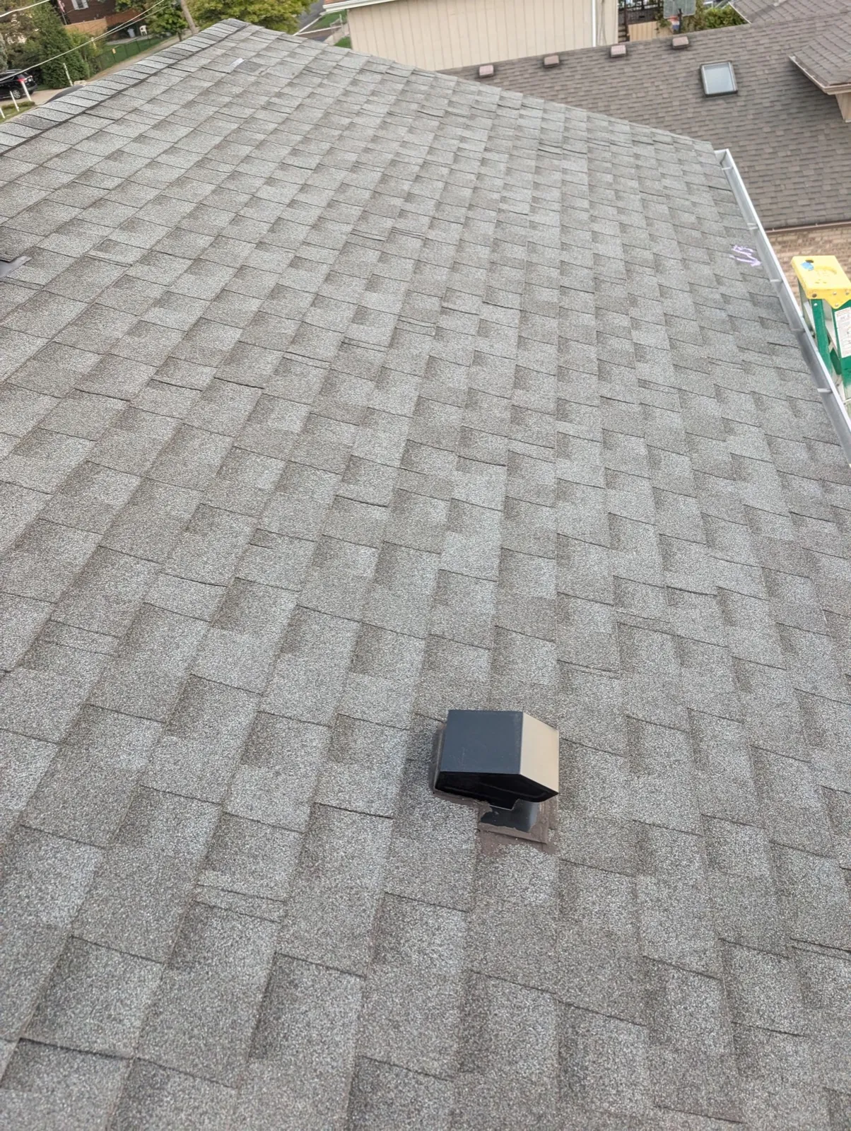 A close-up view of a gray asphalt architectural shingle roof with a black roof vent in Burbank, IL