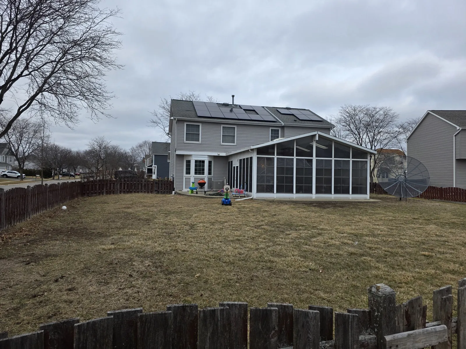 A gray asphalt shingle roof with solar panels on a two-story home in Carol Stream, IL