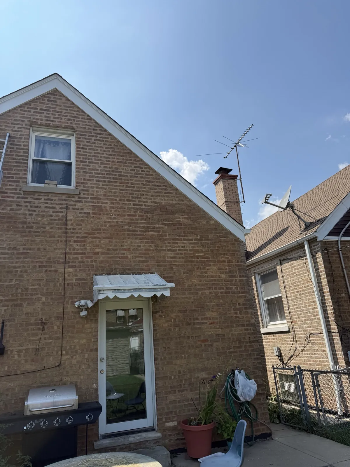 A view of a brick home featuring a new asphalt shingle roof and a chimney in Cicero, IL
