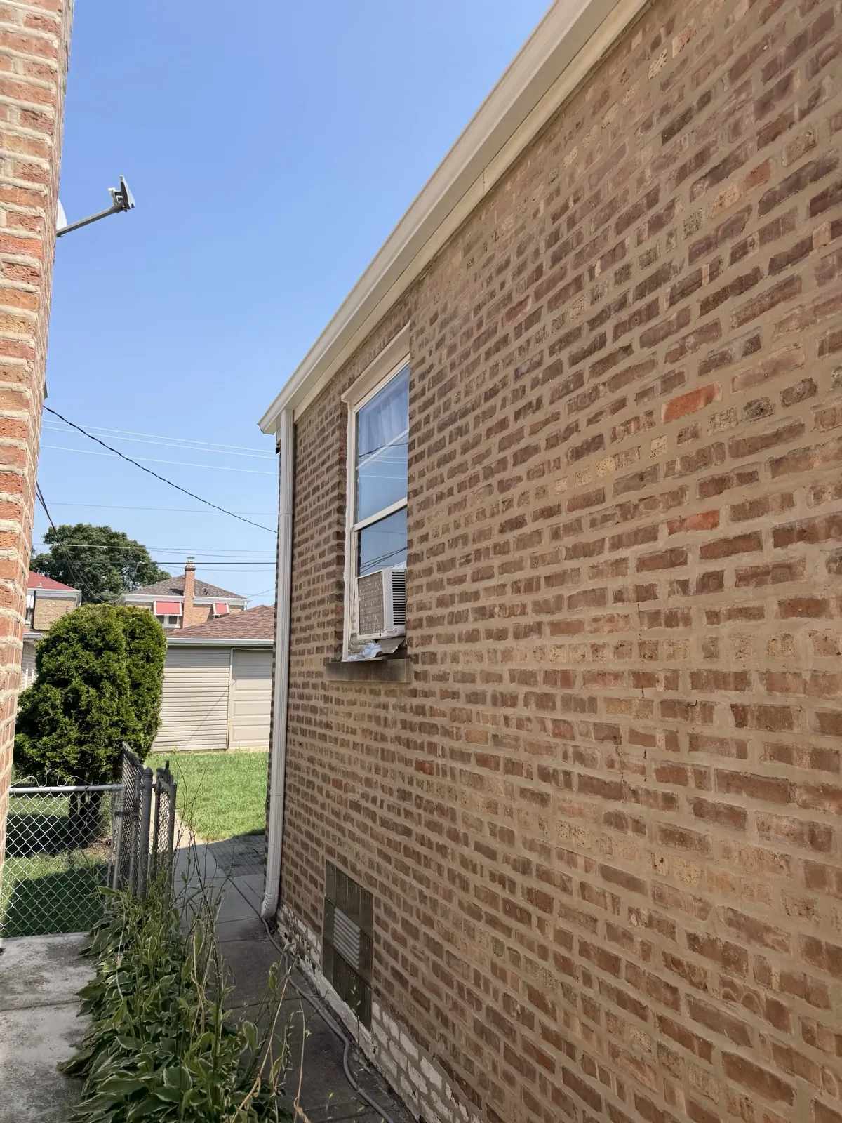 A brick exterior wall featuring a window with an air conditioning unit in Cicero, IL