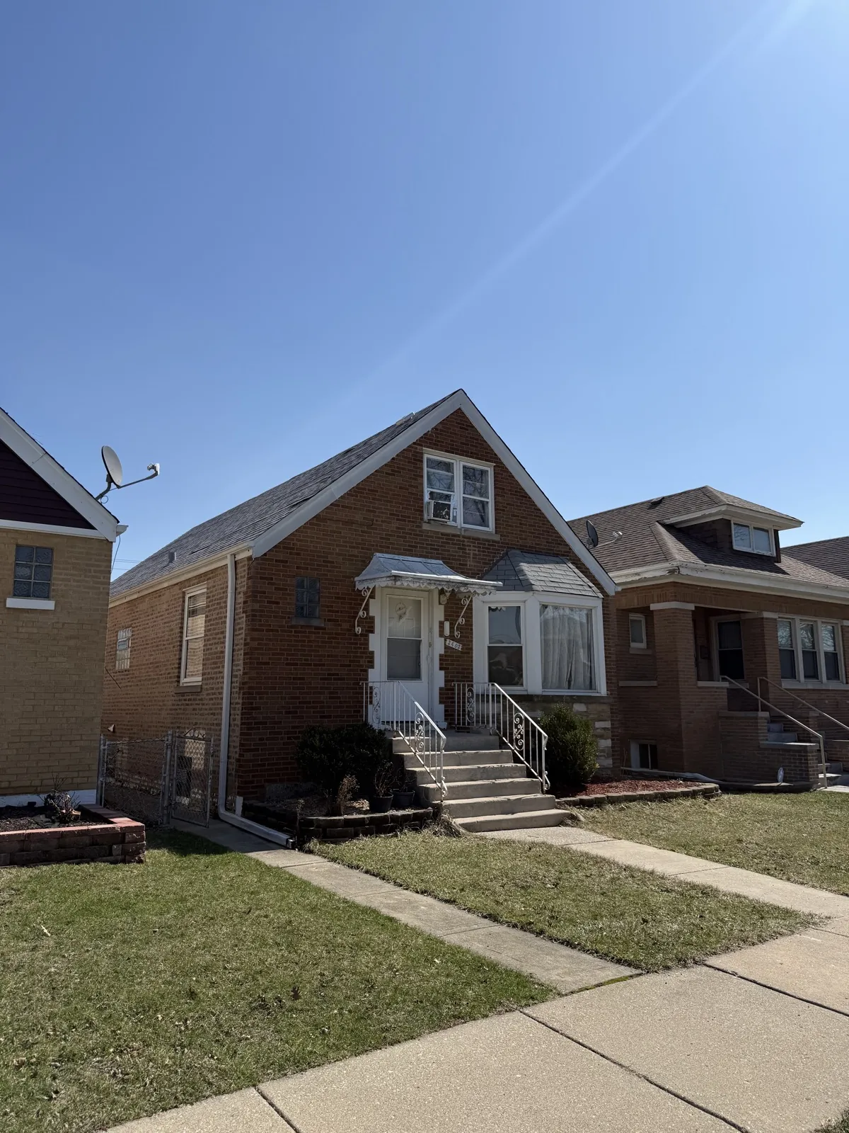 A multi-story brick home featuring a dark asphalt shingle roof in Cicero, IL