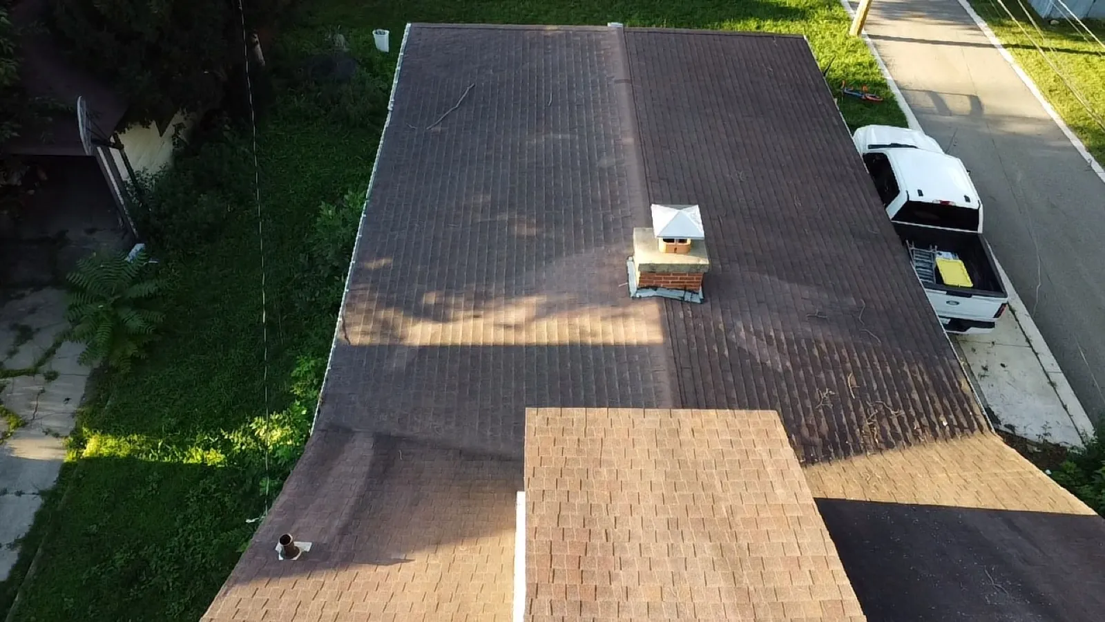 A new asphalt architectural shingle roof installation in progress with a truck parked nearby in Elgin, IL