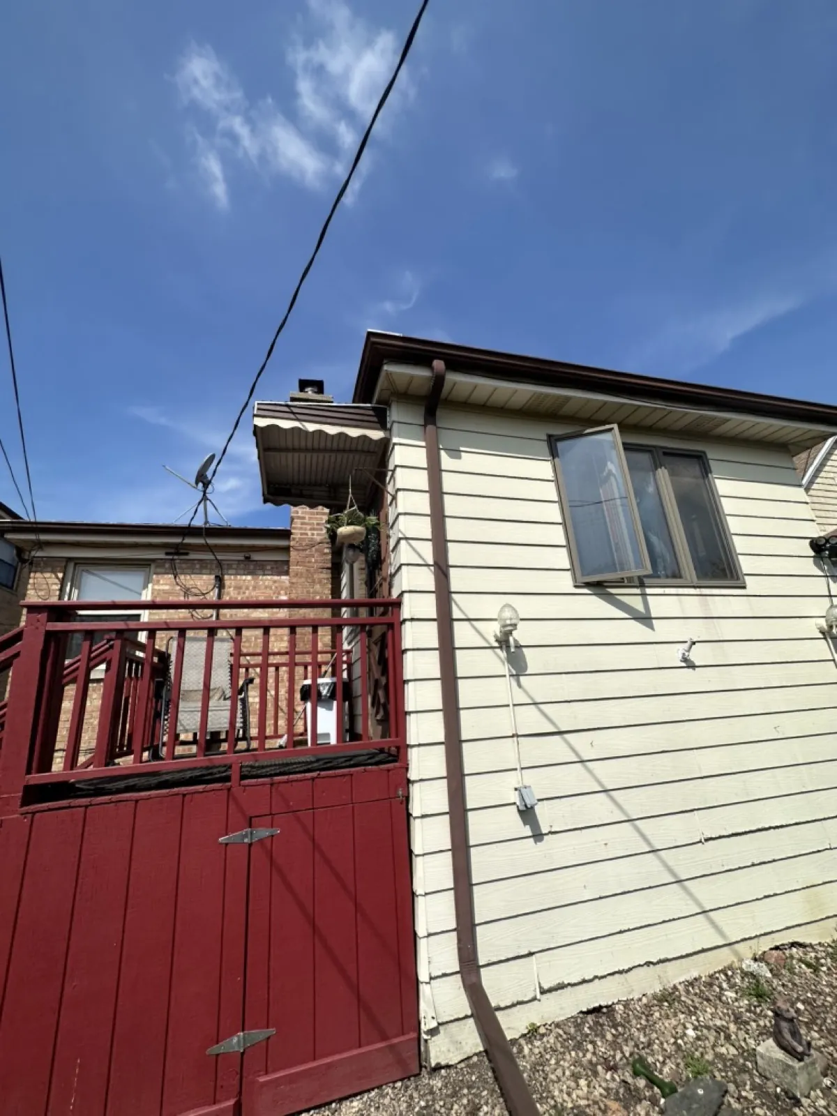A brown gutter system installed on a house with cream-colored siding in Elmwood Park, IL