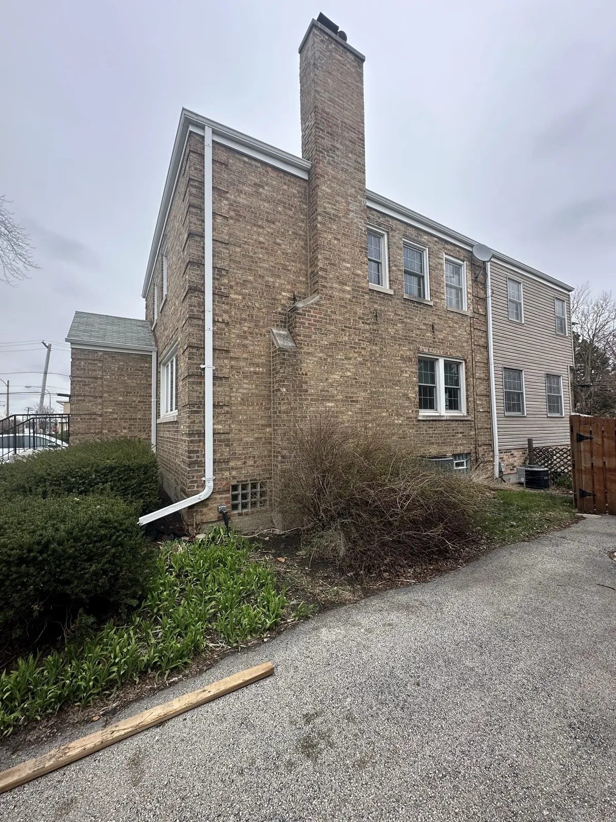A view of a multi-story brick home featuring a new asphalt shingle roof and white gutters in Evergreen Park, IL