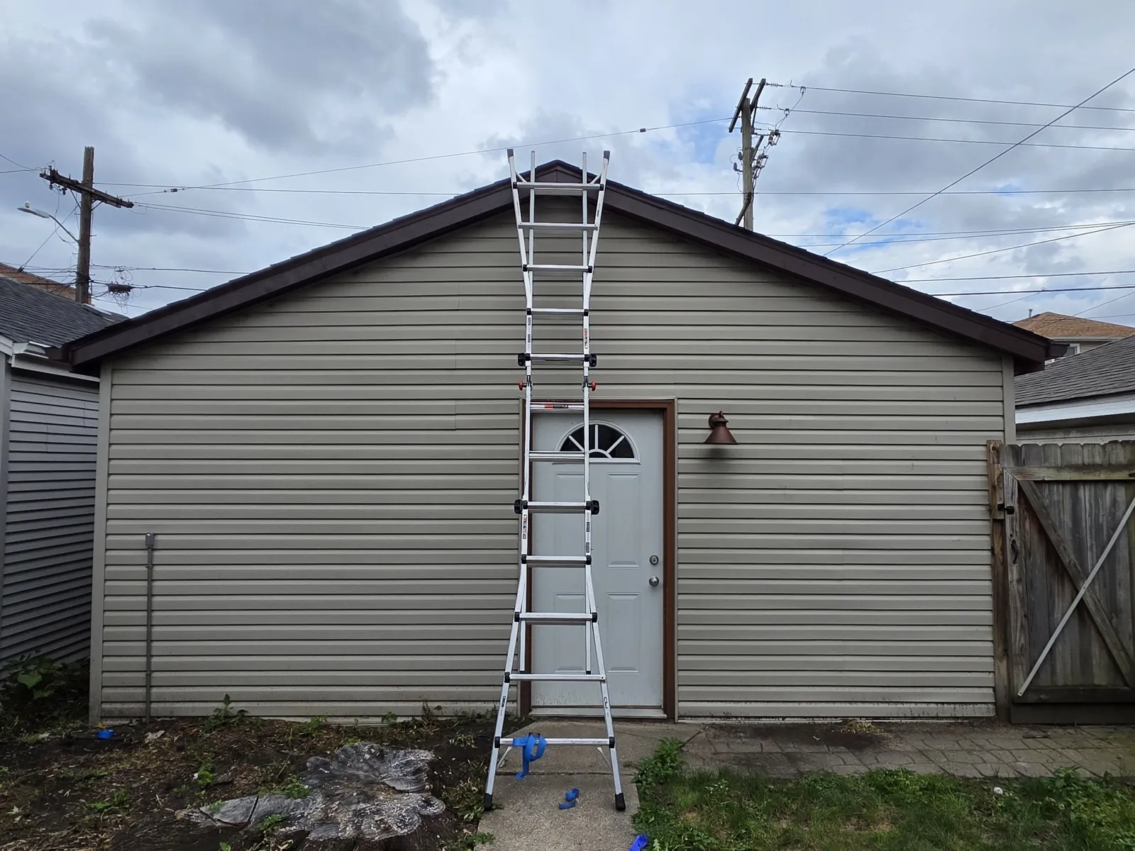 Vinyl siding installation on a garage with a ladder positioned in front of the door in Forest Park, IL