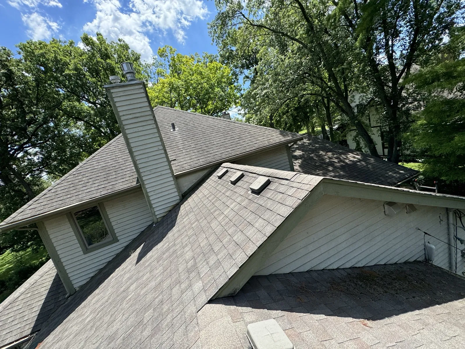 A gray asphalt architectural shingle roof on a multi-level home with white siding in Glen Ellyn, IL