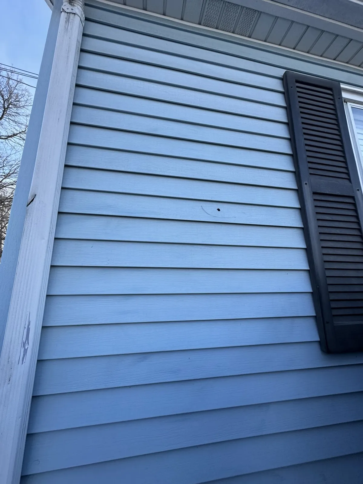 Blue vinyl siding installed on a home exterior with a black shutter in Joliet, IL