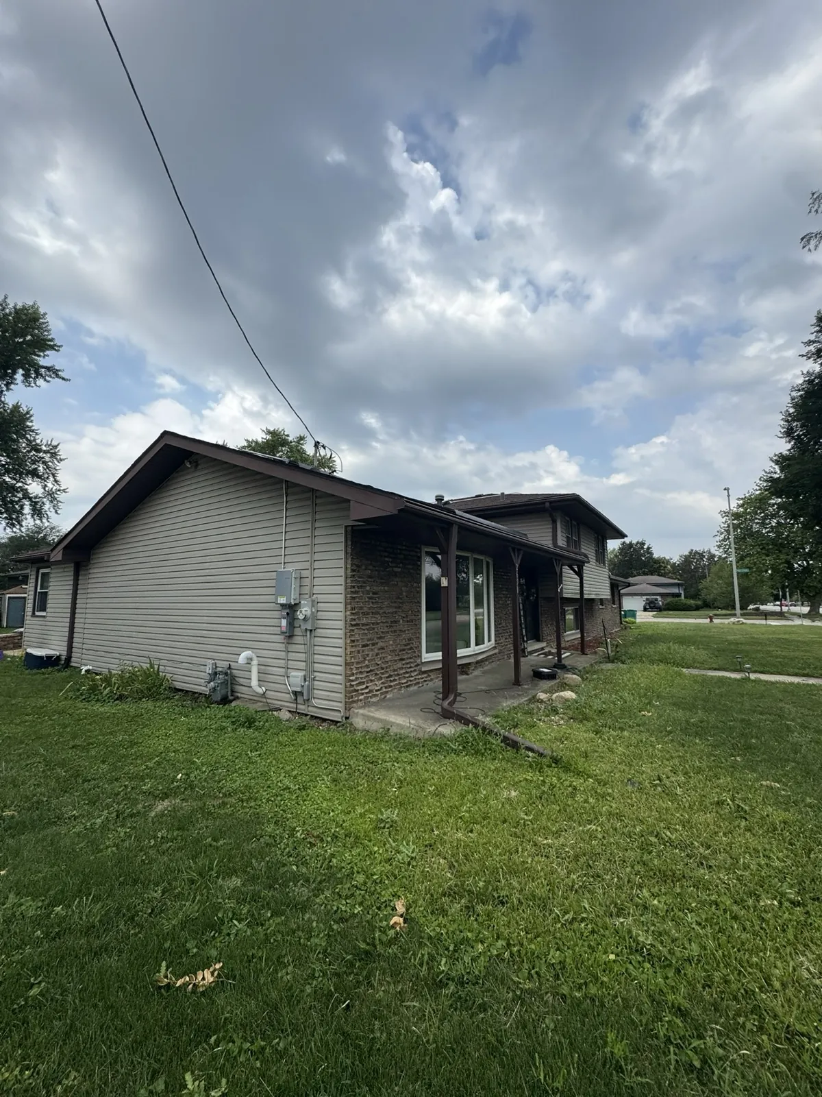 New gray vinyl siding on a single-story home with a brick accent wall in Joliet, IL