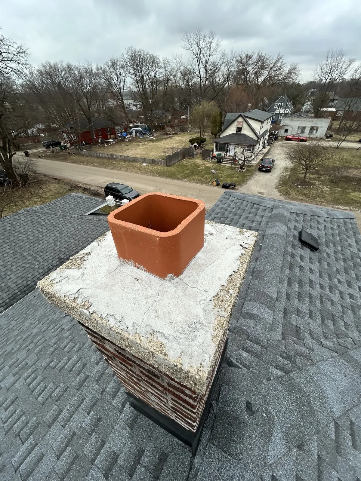 A gray architectural shingle roof featuring a brick chimney with a terracotta-colored chimney pot in Lockport, IL