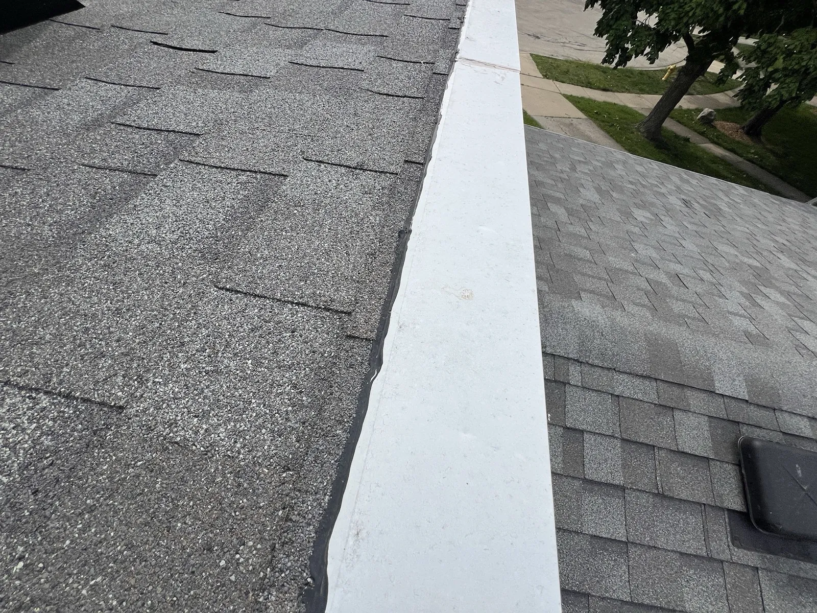 A close-up view of a new asphalt architectural shingle roof with a white ridge cap in Lombard, IL