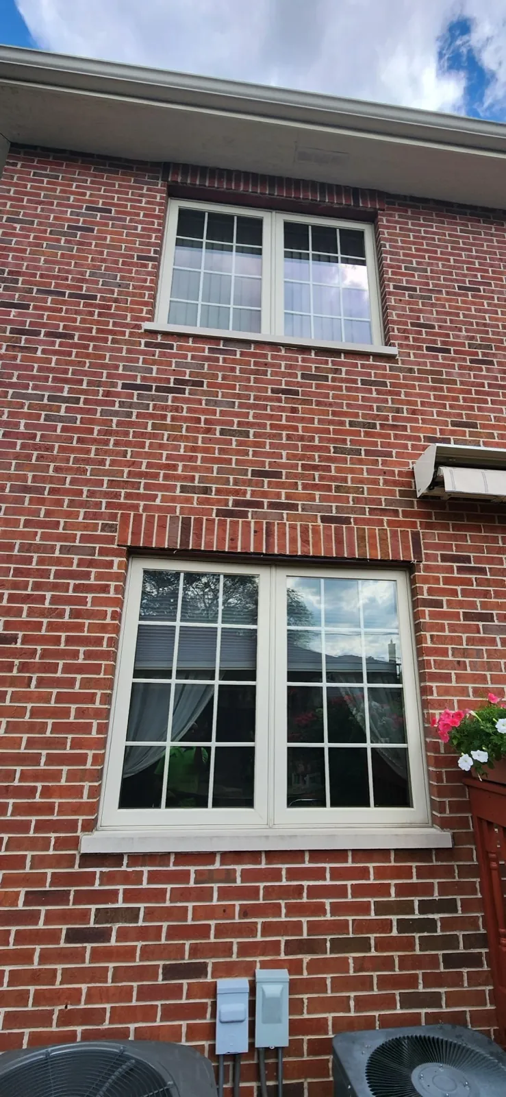 A brick exterior wall featuring two white-framed windows in Norridge, IL