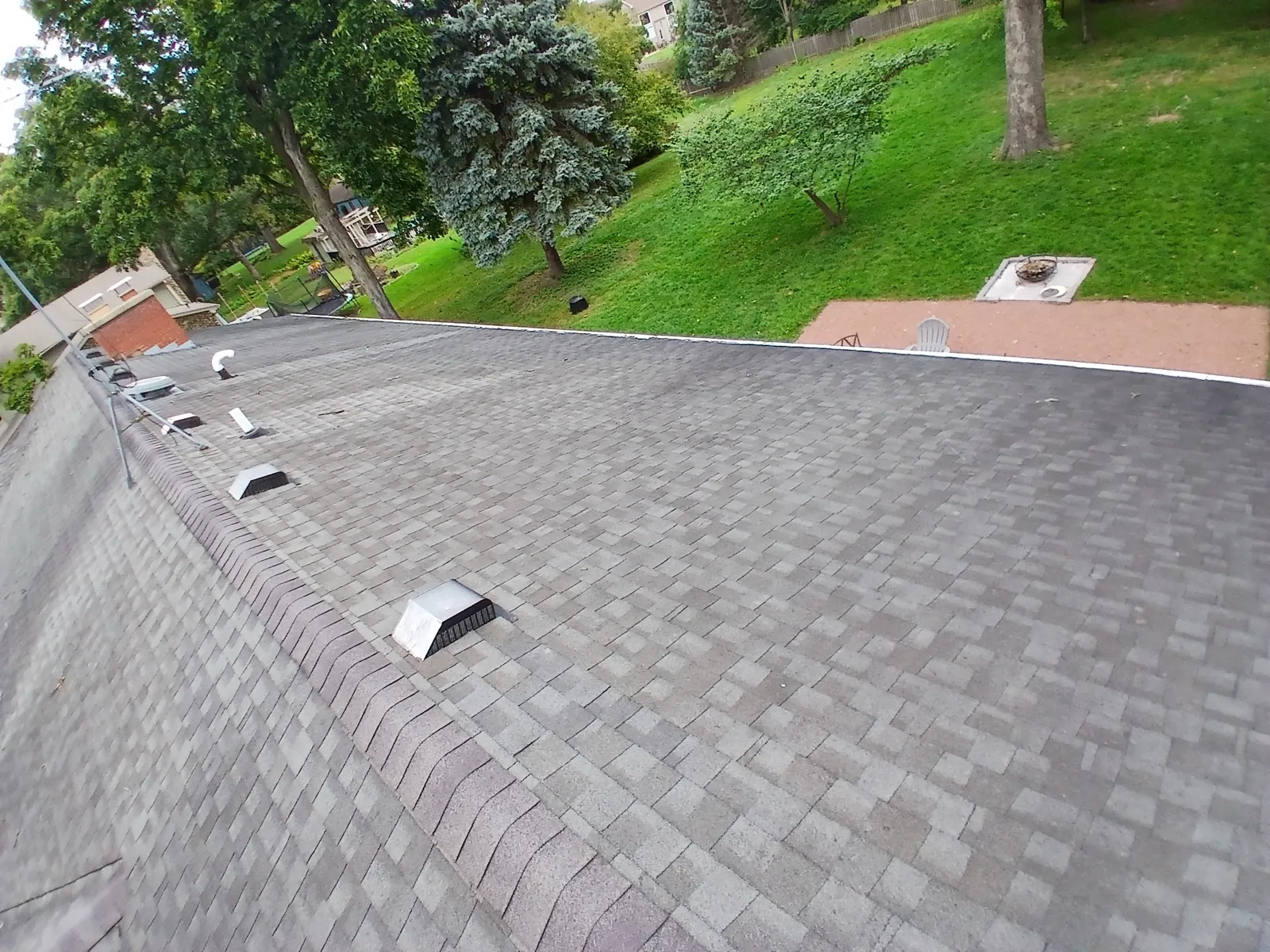 A gray asphalt architectural shingle roof on a house with a sloped yard in North Aurora, IL