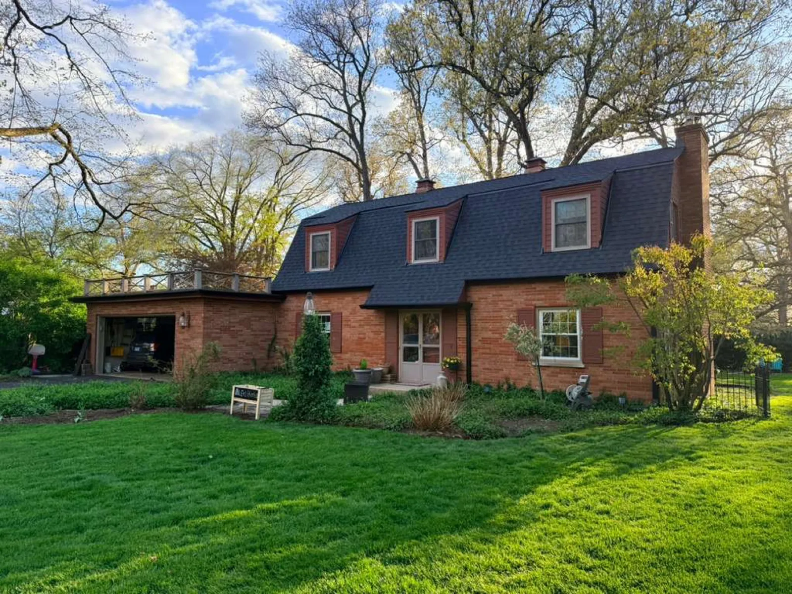 New charcoal architectural shingle roof on a brick cottage with dormer windows in North Aurora, IL