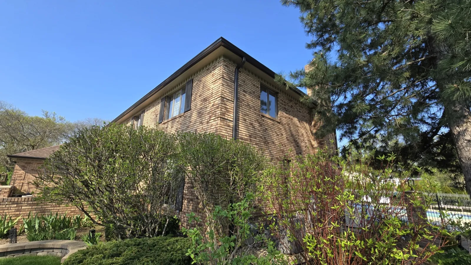 A two-story brick home with a dark shingle roof and integrated gutters in Oak Brook, IL