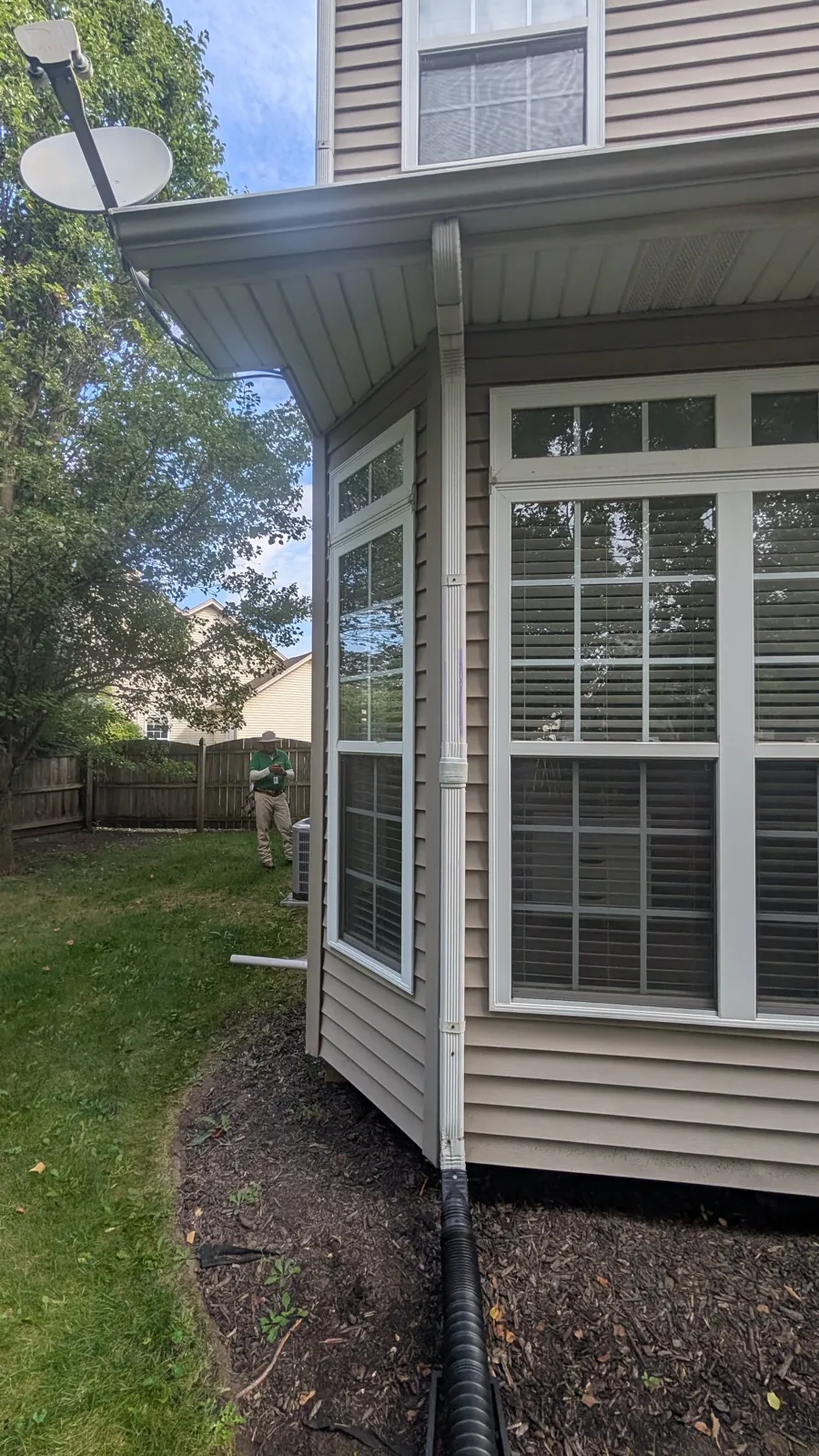 A white gutter system and downspout installed on a house with vinyl siding in Oswego, IL