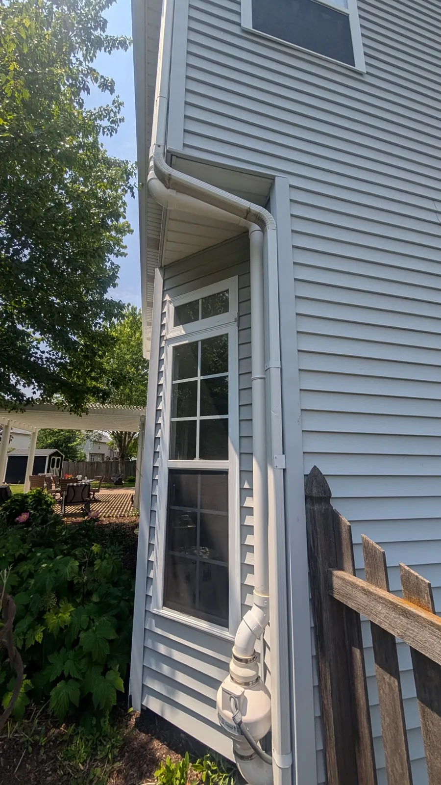 White vinyl gutters and downspouts installed on a house with light gray siding in Oswego, IL