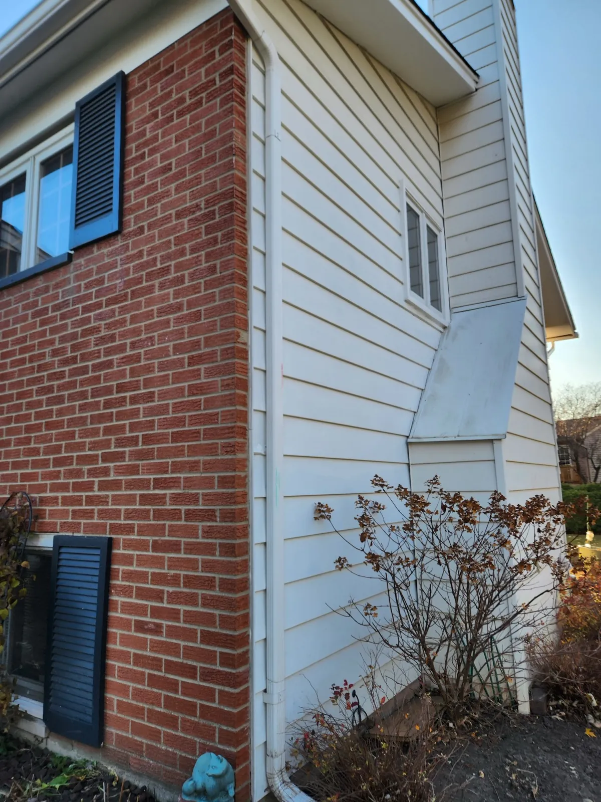 White gutters installed on a house with vertical siding and brick siding in Palatine, IL
