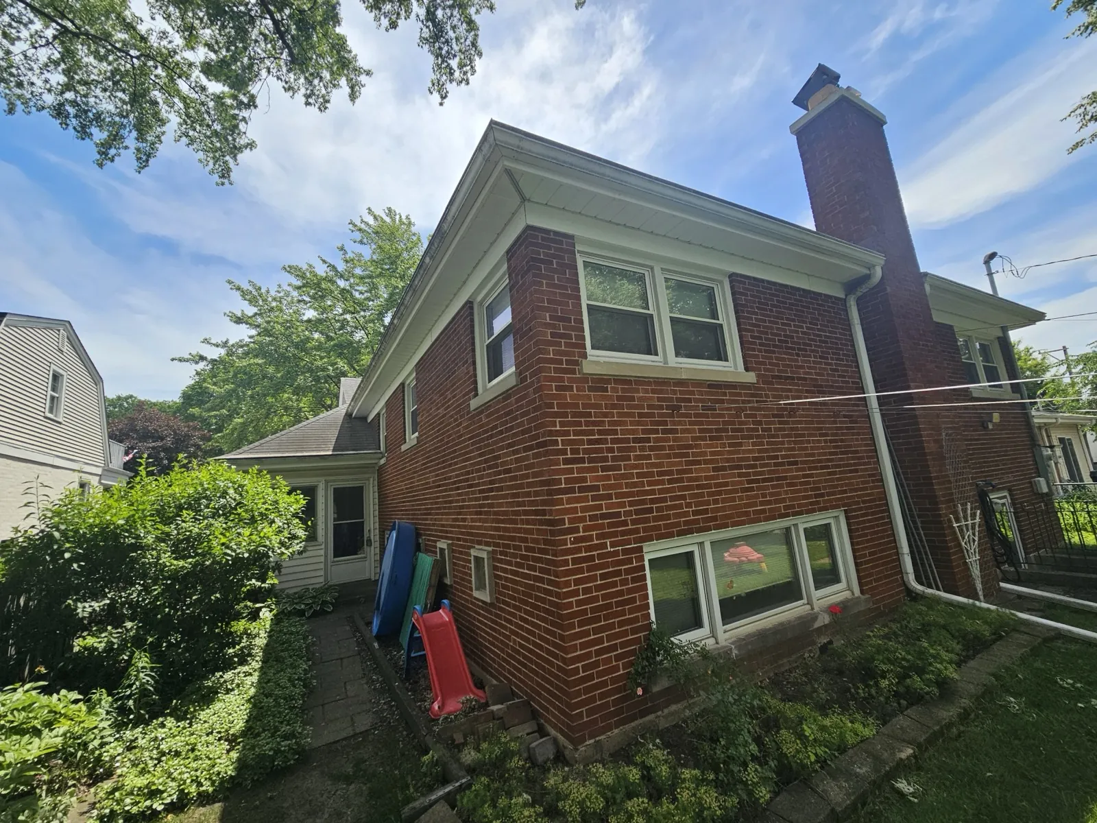 A view of a brick home featuring a new asphalt shingle roof and a large chimney in Park Ridge, IL