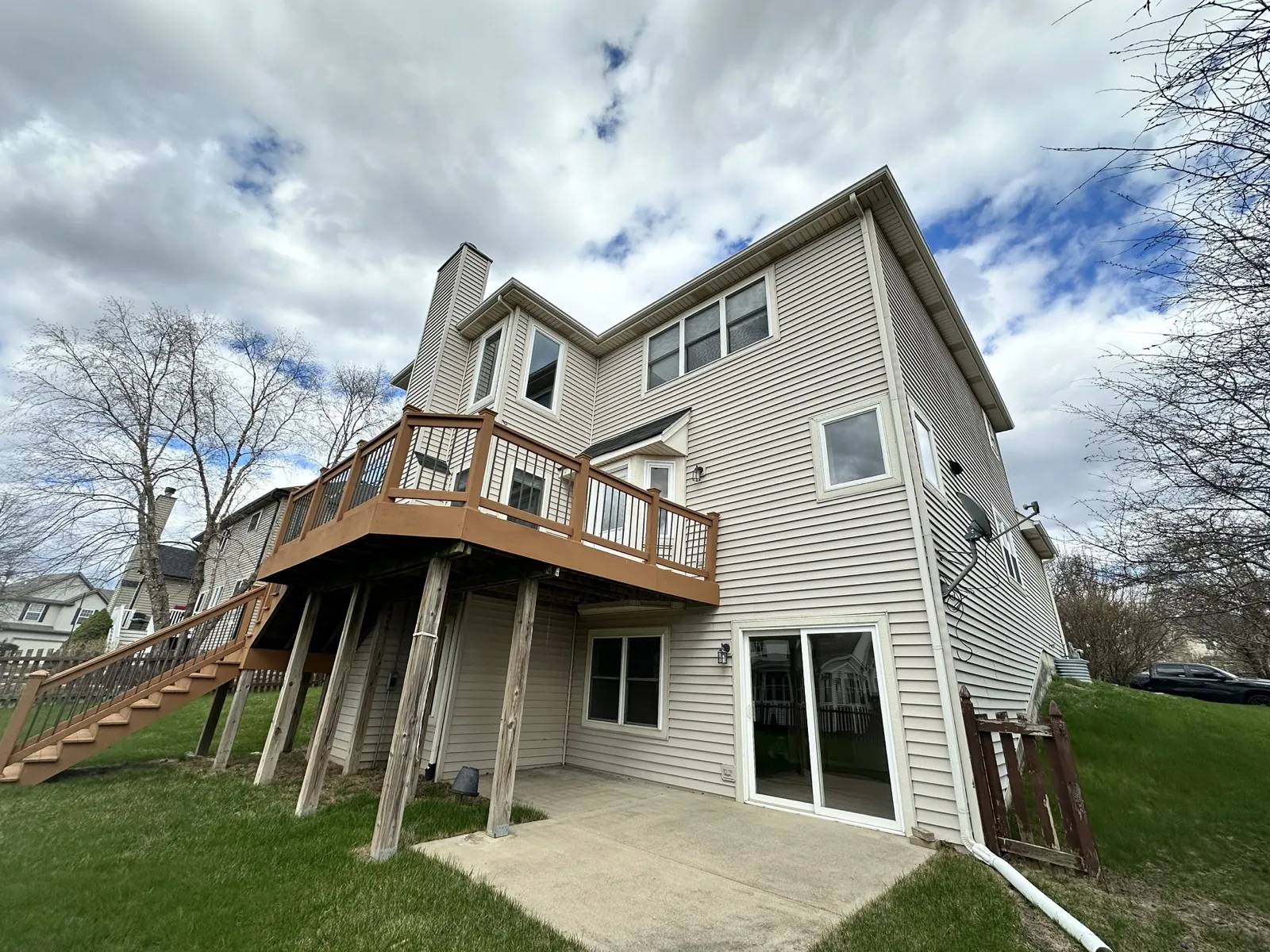 A two-story home featuring beige vinyl siding and a large wooden deck in South Elgin, IL