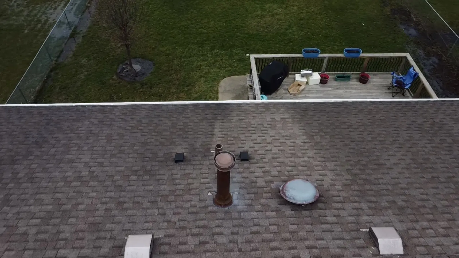 A view of a gray asphalt architectural shingle roof featuring a chimney and skylight in Streamwood, IL
