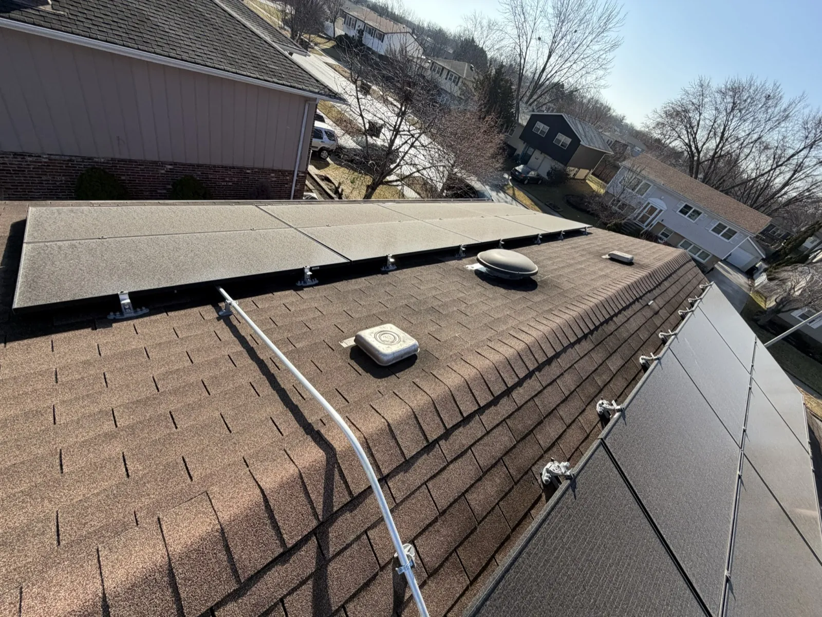 A brown asphalt shingle roof featuring a skylight and integrated solar panels in Tinley Park, IL