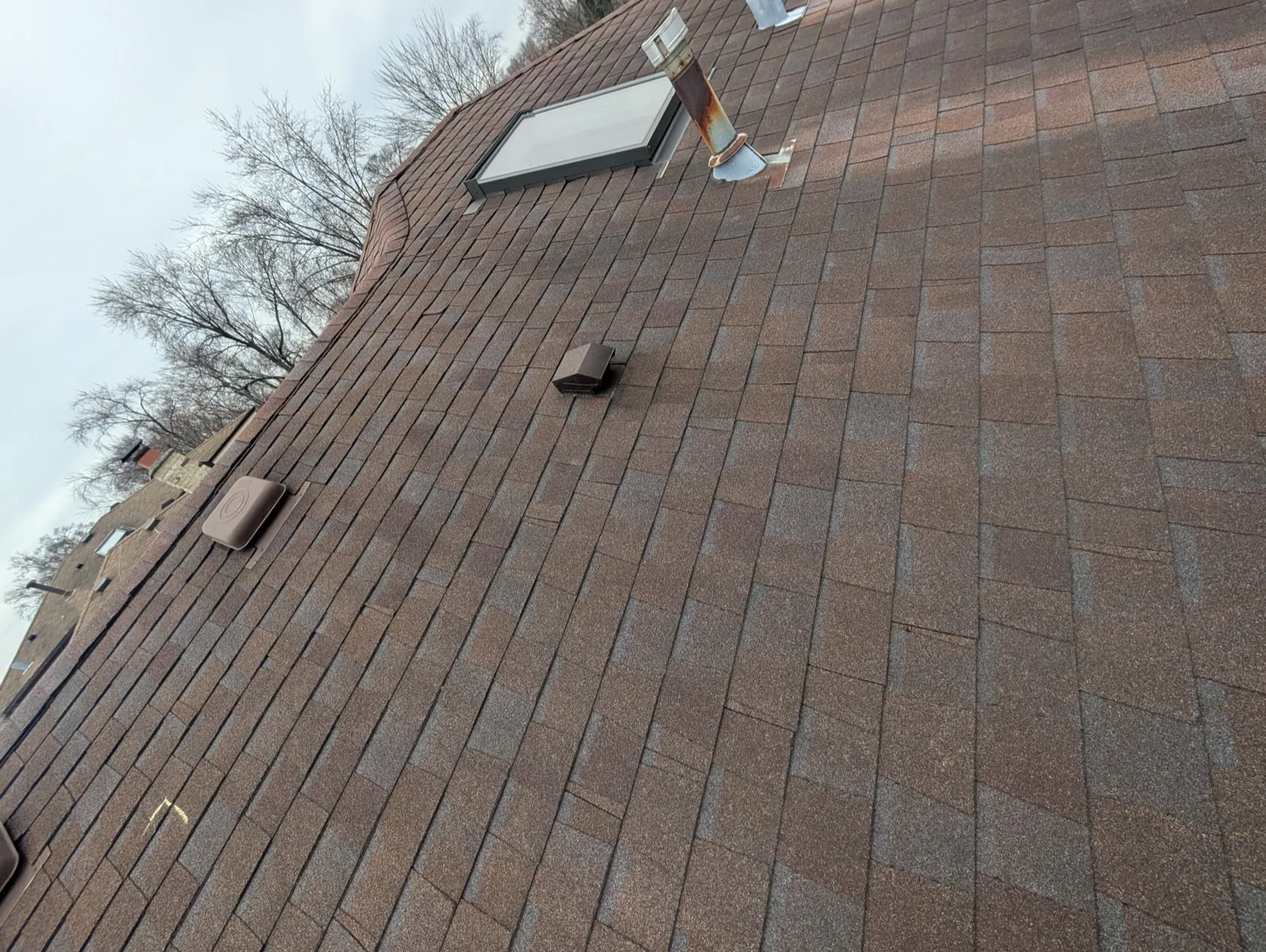 A brown architectural shingle roof featuring a skylight and ventilation vents in Tinley Park, IL
