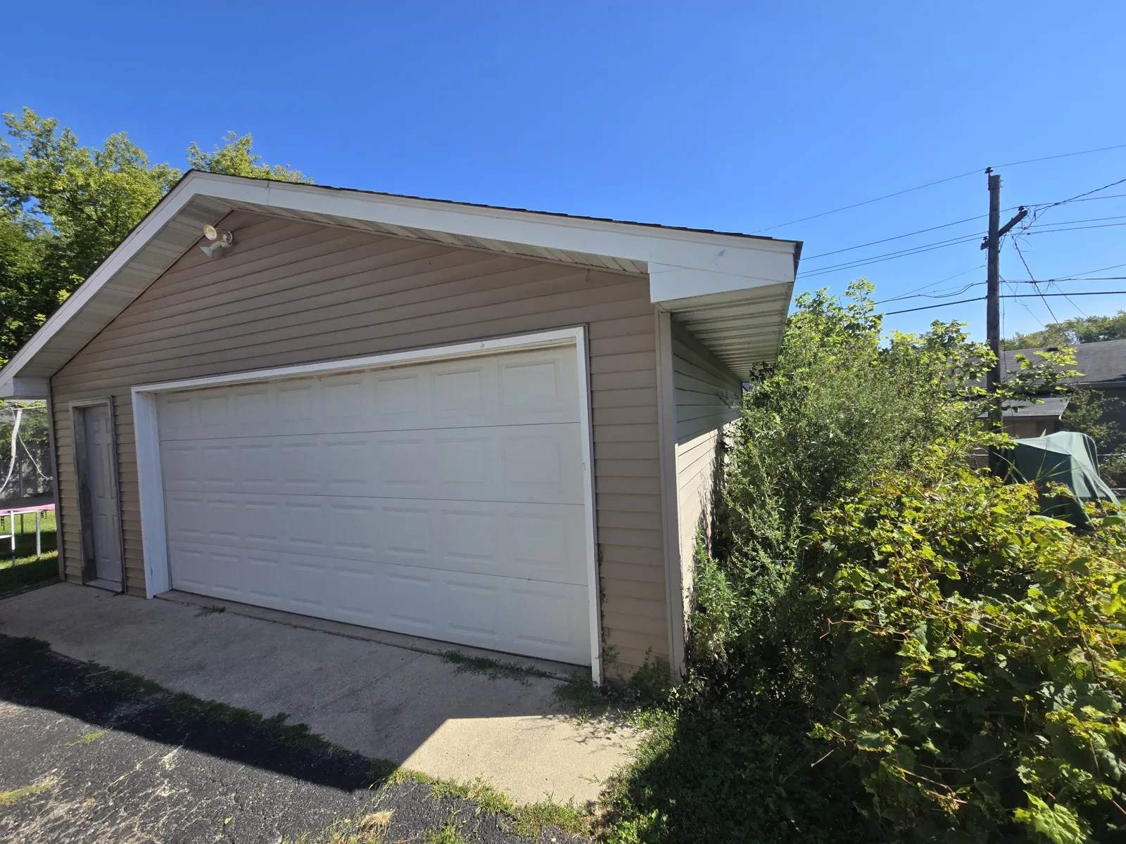 New tan vinyl siding on a garage with a white garage door in Waukegan, IL