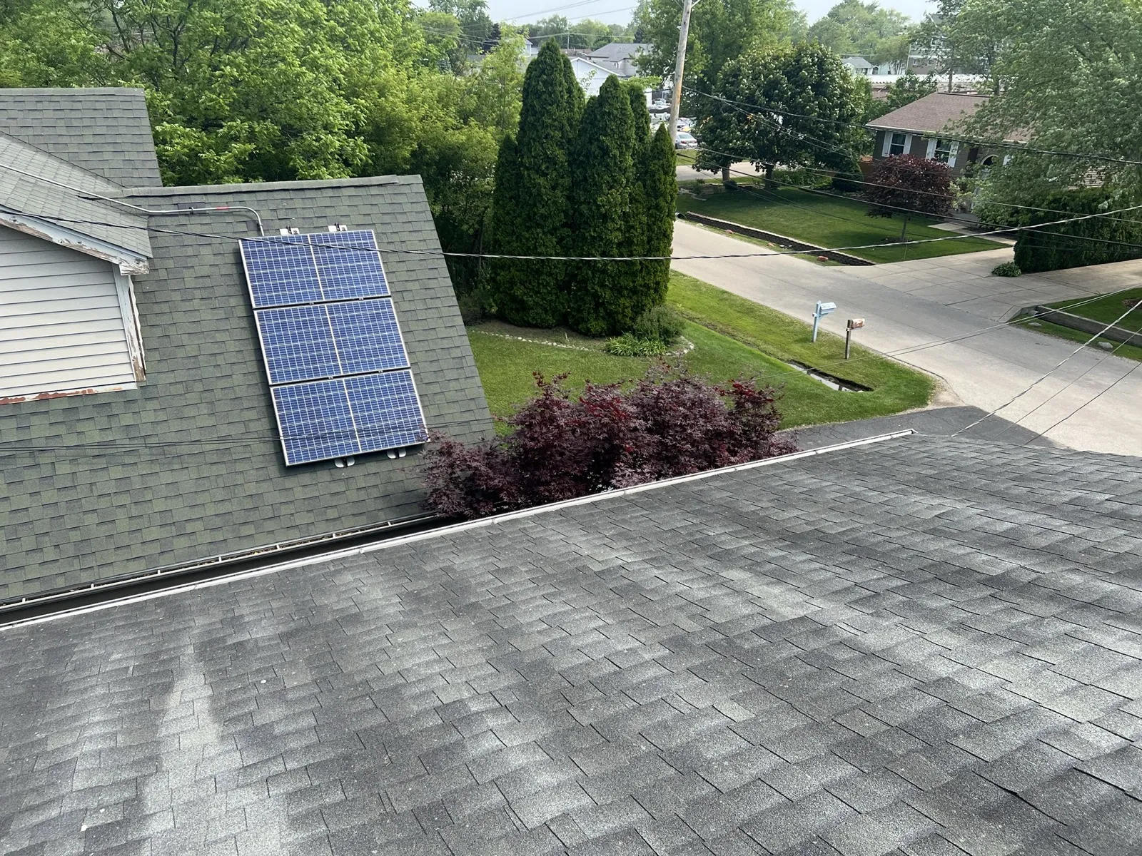 A gray asphalt architectural shingle roof with a view of a neighboring home featuring solar panels in Waukegan, IL