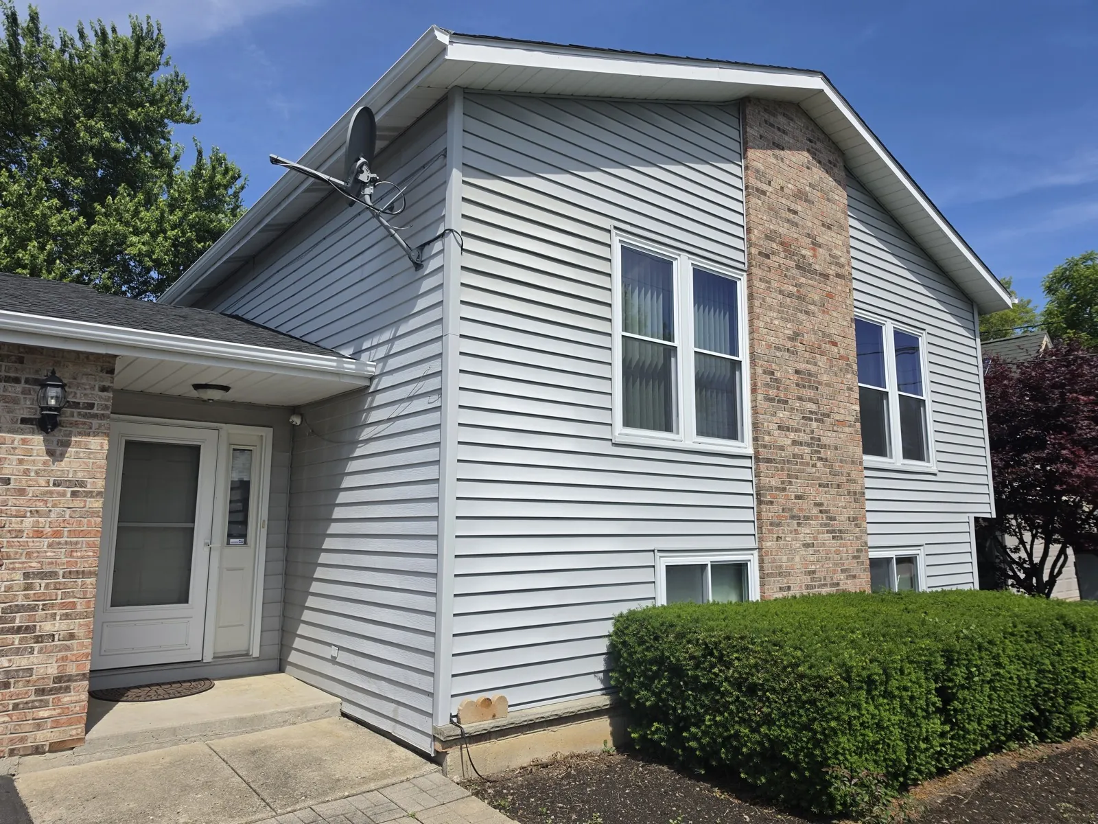 Gray vinyl siding installed on a two-story home with brick accents in Waukegan, IL