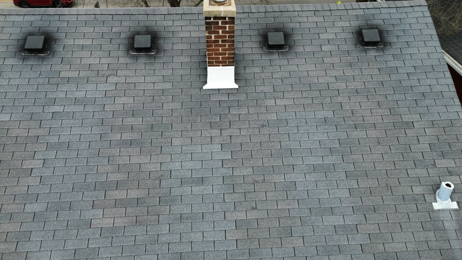 A gray asphalt architectural shingle roof featuring a brick chimney and ventilation systems in Wheaton, IL