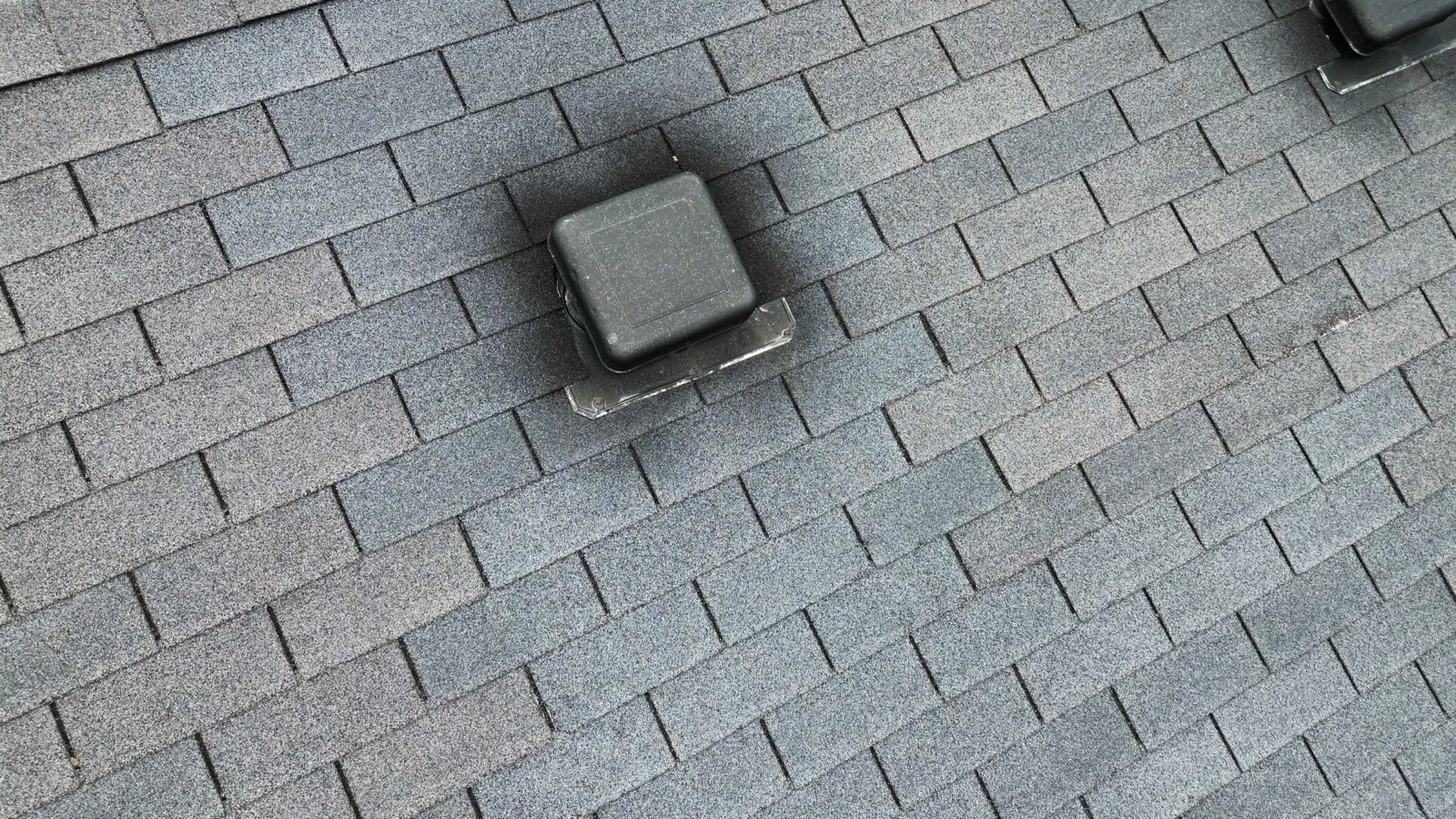 Close-up of a charcoal gray architectural shingle roof with a black pipe boot in Wheaton, IL