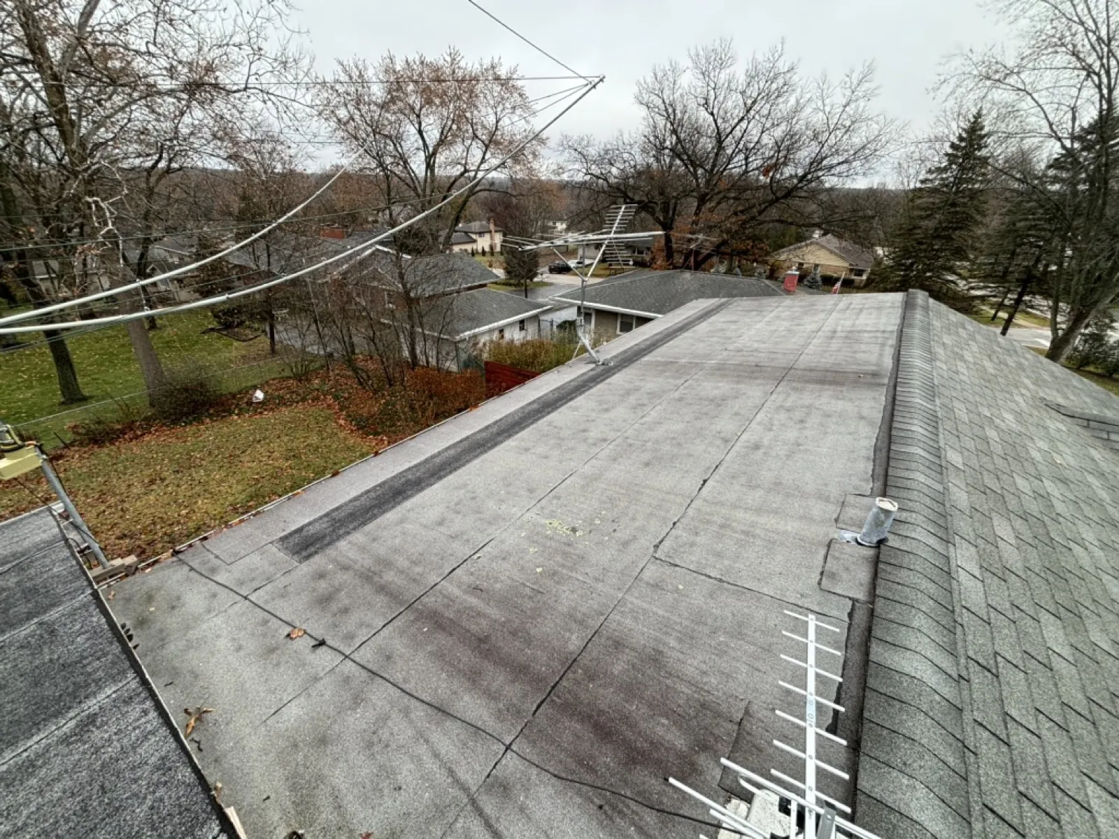 A flat roof section with asphalt shingles and a sloped shingled roof in Winfield, IL