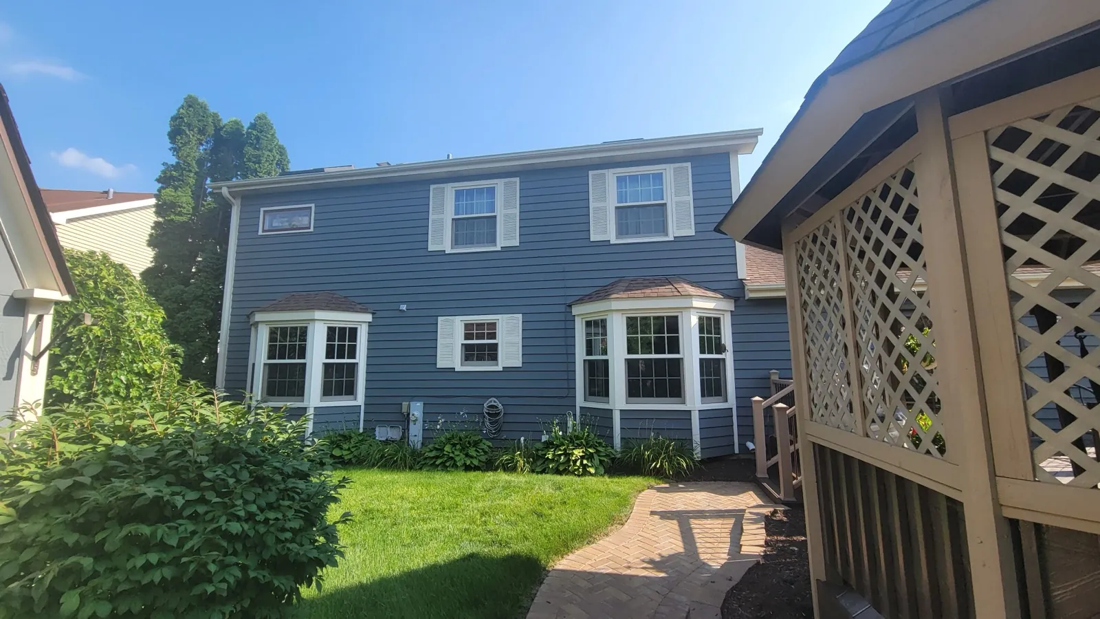 Blue vinyl siding on a two-story home with white trim and bay windows in Winfield, IL