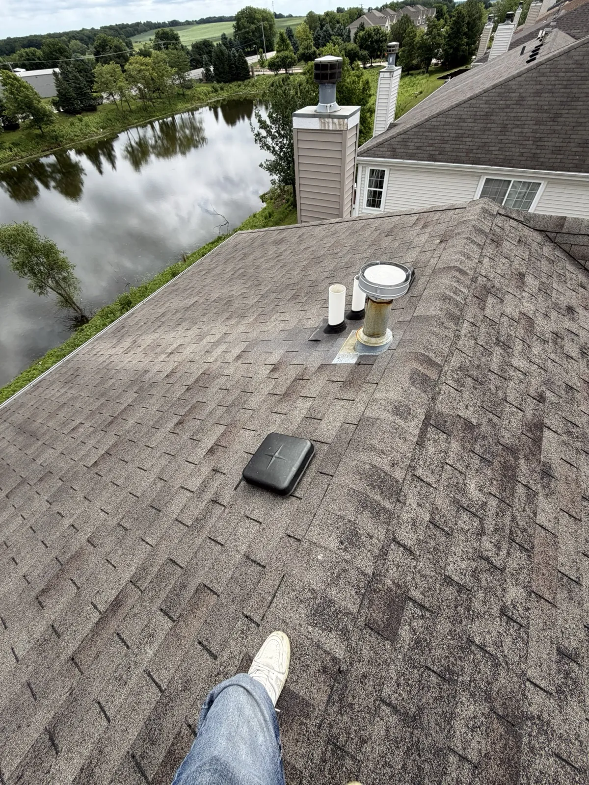 New charcoal architectural shingle roof with installed vents and chimney flashing in Yorkville, IL